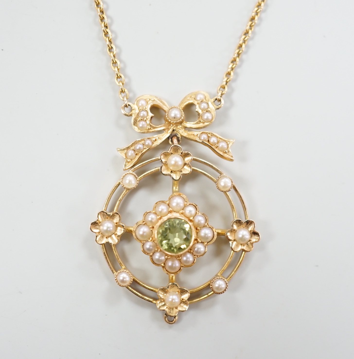 An Edwardian yellow metal, peridot and seed pearl cluster set pendant necklace, overall 55cm, gross weight 5.7 grams.